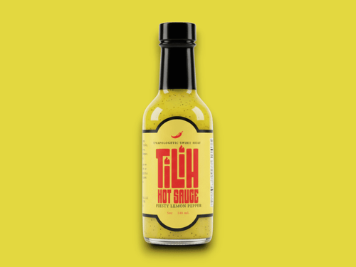 Close-up of Lemon Pepper Hot Sauce bottle on yellow background